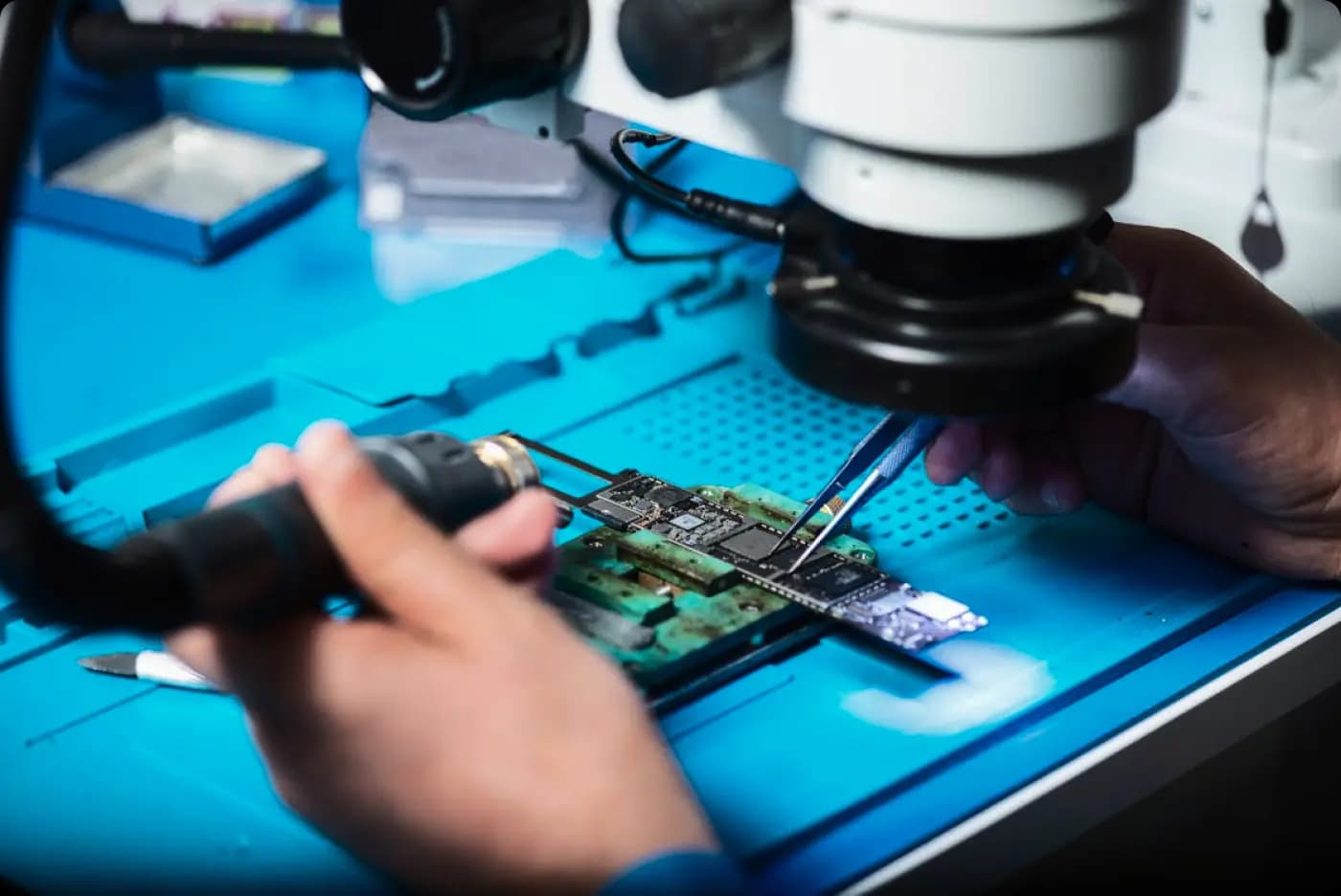 Technician assembling electronic circuit board under microscope